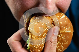 The hungry young man aggressively eats a burger. Fast food