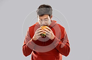 Hungry young man eating hamburger