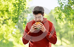 Hungry young man eating hamburger