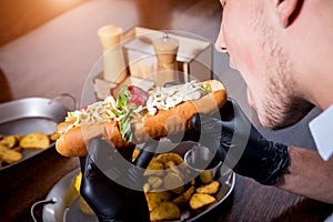 Hungry young man eating a hot dogs in cafe. Restaurant