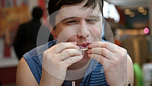 Hungry young man eating meal of fried chicken in fast food restaurant