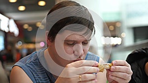 Hungry young man eating meal of fried chicken in fast food restaurant