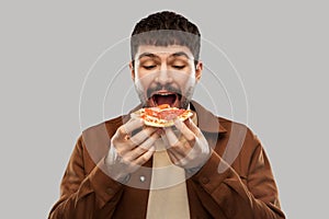 Hungry young man eating pizza
