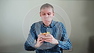 Hungry young man greedily eating the sandwich