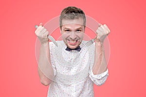 Hungry young man holding fork and knife on hand ready to eat, licking lips.