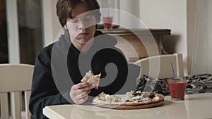 Hungry young man insatiably eating a pizza in cafe