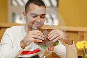 Hungry young man in resaurant eat sandwich photo