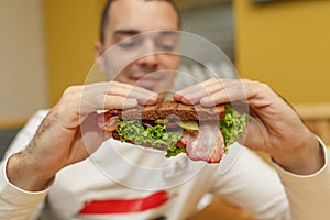 Hungry young man in resaurant eat sandwich