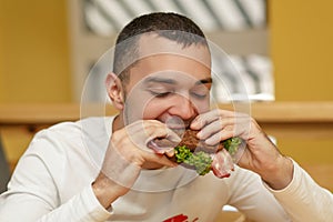 Hungry young man in resaurant eat sandwich