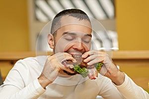 Hungry young man in resaurant eat sandwich photo