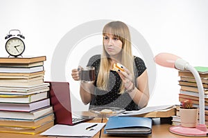 Hungry young teacher sitting wearily with a sandwich and coffee