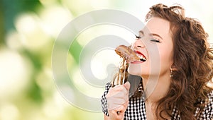 Hungry young woman eating meat on fork over green