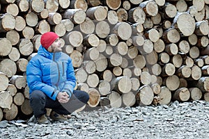 Hunkering worker having a rest at pile of logged