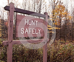 A `HUNT SAFELY` sign on in the fall woods