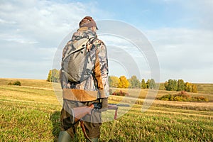 Hunter with a backpack and a hunting gun in autumn season