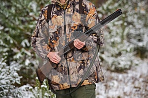 Hunter with a backpack and a hunting gun in the winter forest.