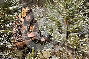 Hunter with a backpack and a hunting gun in the winter forest.