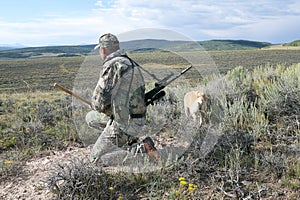 Hunter in camouflage scanning an arid landscape