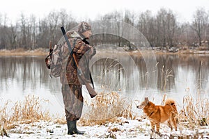 Hunter with dog on the riverbank
