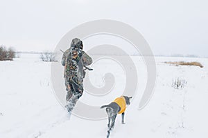 Hunter and dog walking on the snowy field