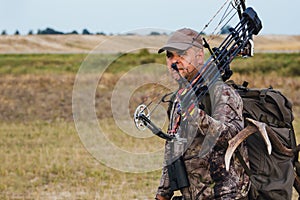 Hunter dressed in camouflage clothing holding a modern bow.