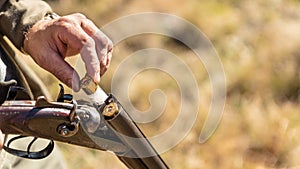 Hunter equips the retro double-barreled shotgun with cartridges, close up. Outdoor sports