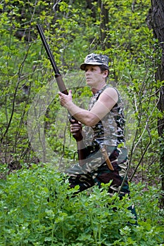 Hunter in forest with gun in hands