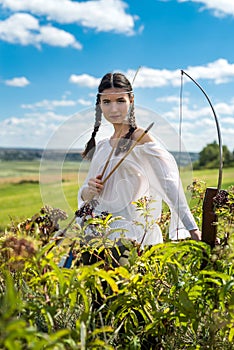 hunter girl shooting bow and arrow in the grassland