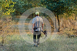 A hunter with a gun in his hands in hunting clothes in the autumn forest in search of a trophy.