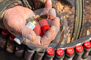 A hunter with a gun in his hands in hunting clothes in the autumn forest in search of a trophy.