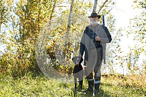 Hunter and his dog looking for trophy in forest