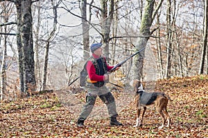 Hunter and hunting dog chasing in the forest