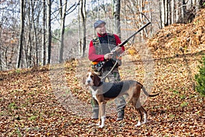 Hunter and hunting dog chasing in the forest.