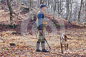 Hunter and hunting dog chasing in the forest