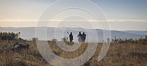 Hunter, huntsman and tracker inspect the mountainous terrain in search of animals