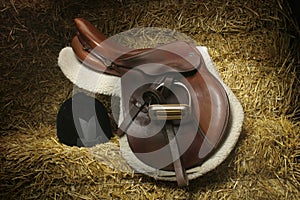 Hunter/jumper saddle and hunt cap on bales of straw photo