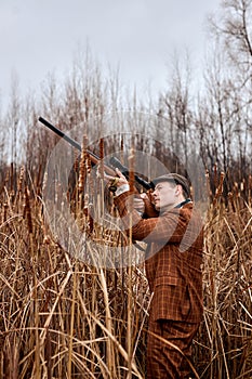 Hunter male. Shooter sighting in target. Hunting period. Male with gun in field.