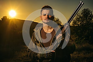 Hunter with Powerful Rifle with Scope Spotting Animals. Rifle Hunter Silhouetted in Beautiful Sunset.