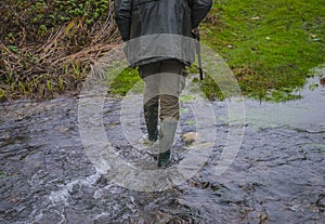 Hunter with rifle passe through the river