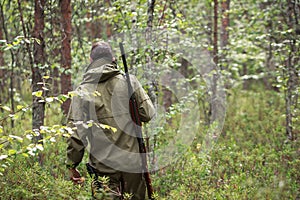 Hunter with shotgun walking in the forest. Hunting season. Fowling piece. Wild nature background