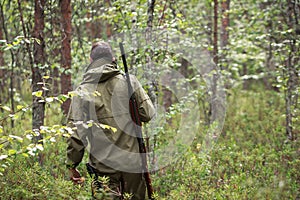 Hunter with shotgun walking in the forest. Hunting season. Fowling piece. Wild nature background photo