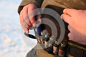 Hunter takes out a hunter cartridge from the bandolier close up view.