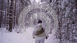 A Hunter walks along a snow-covered forest path, and a dog runs in front.