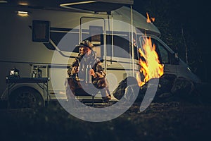 Hunter Wearing Camouflage Coating Burning Campfire Next to His Motorhome Camper Van RV