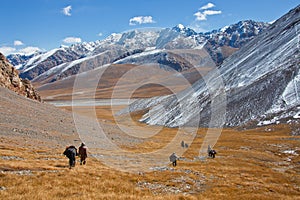 Hunters with horses descend from the mountains into the valley.