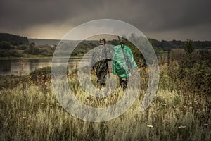 Hunters with hunting ammunition guns going through rural field during hunting season in overcast day