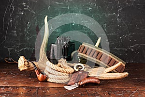 Hunting composition with a horn and bandoleer. Compass and binoculars. Rope and elk horn photo