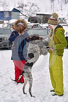 Hunting dog stands on hind legs in front of a girl in winter clothes