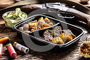 Hunting eddititon lunch in portable take away plastic box consisting of delicious roasted potatoes with wild game goulash stew and