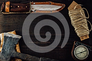 Hunting knife, military compass, a linen rope and small axe on the table. photo